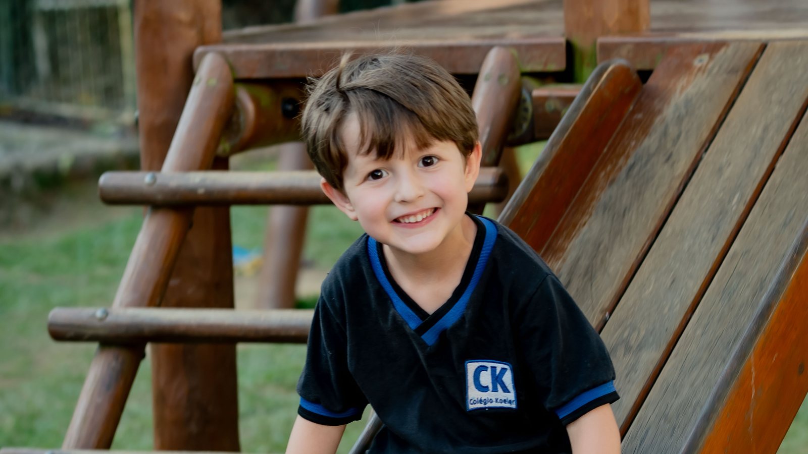 Aluno do Colégio Koeler sorrindo no escorregador do parque